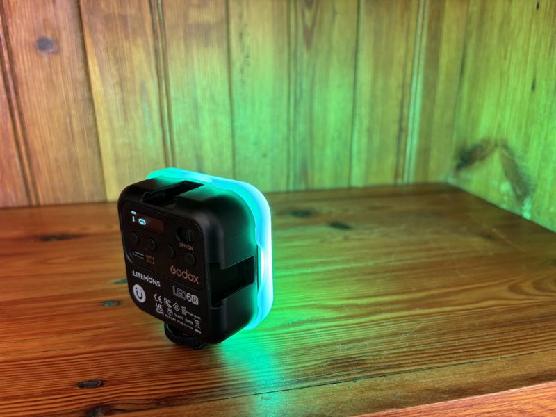 Godox Litemons LED6R light glowing green on a pine shelf