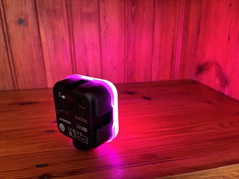 Godox Litemons LED6R light glowing magenta on a pine shelf