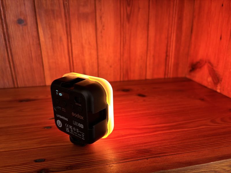 Godox Litemons LED6R light glowing warm orange on a pine shelf