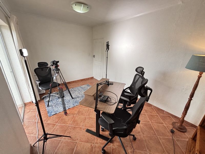 View from the window side of the room towards the door, showing the desk, chairs and camera on a tripod
