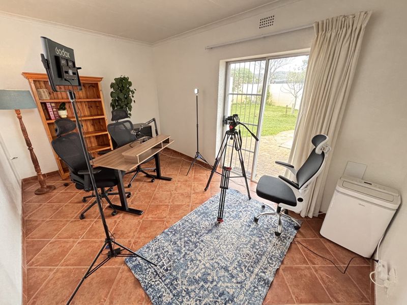 Wide view of the studio with the sliding door onto the garden, the camera on its tripod and the air conditioner in the corner